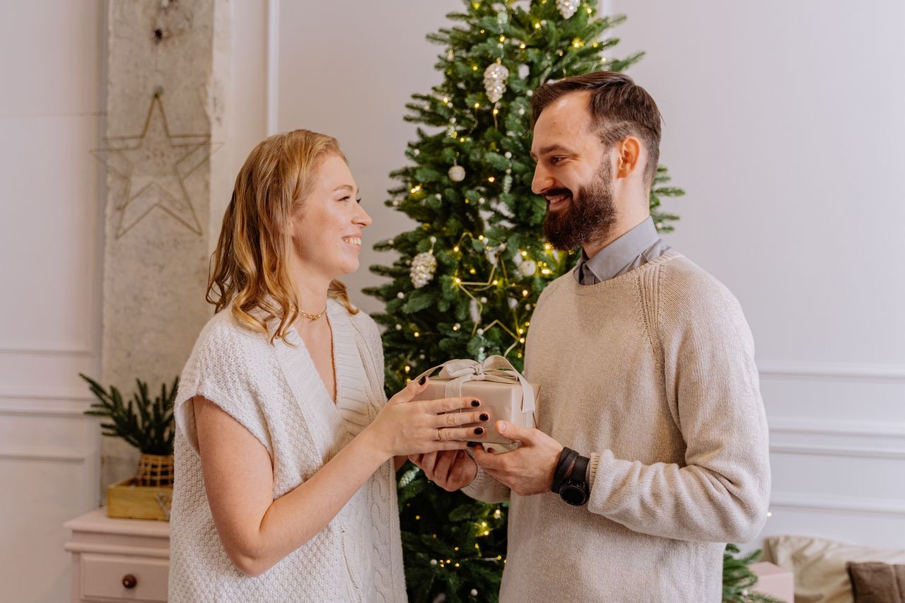 Una pareja se intercambia un regalo junto al árbol de Navidad