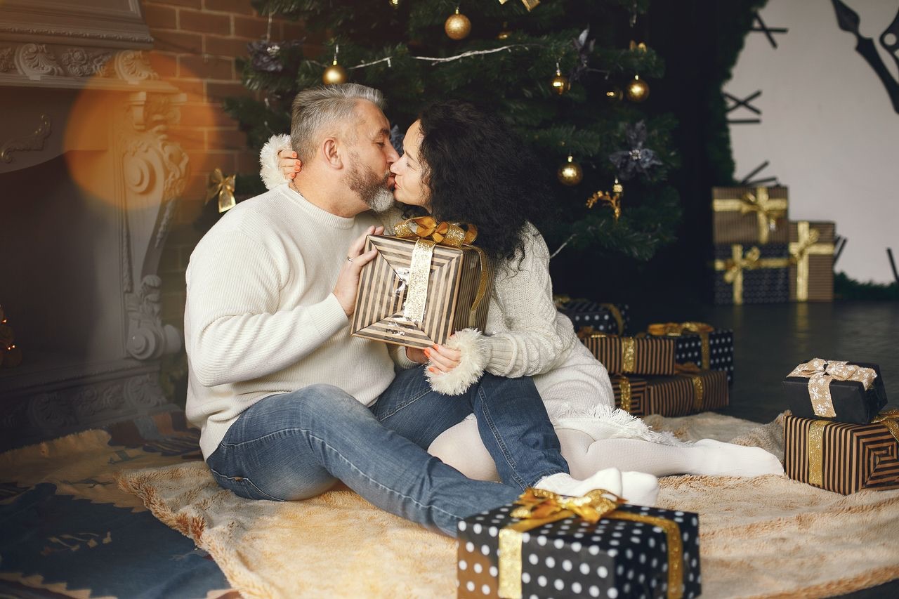 Una pareja con un regalo junto al árbol de Navidad